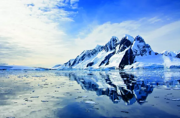 Beautiful snow-capped mountains being reflected in water against the blue sky