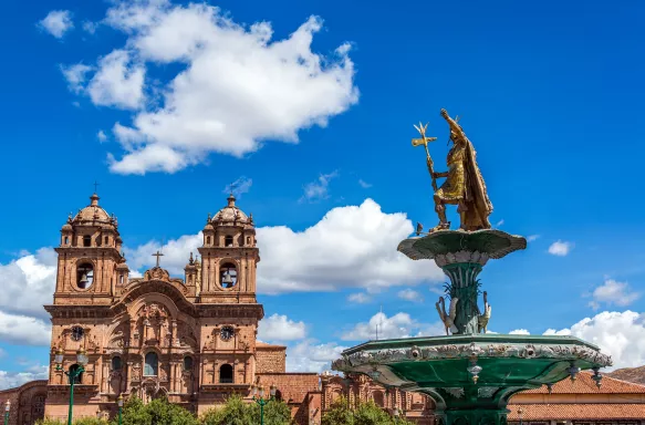 A golden fountain and an impressive religious building in Cuzco Main Square, Peru