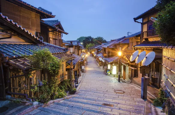 Old street of Kyoto in a Japanese town, lit by street lights under an early evening sky