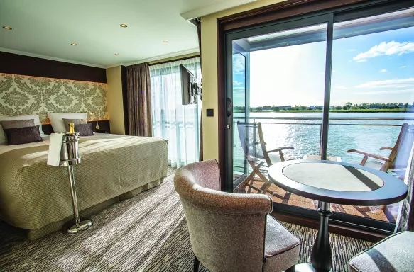Deluxe suite bedroom with private balcony aboard the Thomas Hardy ship
