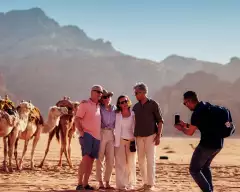 Tour group having their picture taken in the desert of jordan with camels behind