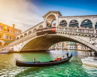 Gondola on Canal Grande with Rialto Bridge at sunset in Venice, Italy
