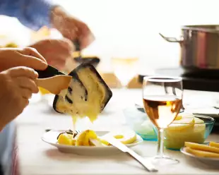 Close-up of family serving Raclette, a traditional Swiss Winter meal