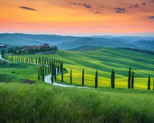 Green grassy hills and curved road of Crete Senesi Asciano in Tuscany
