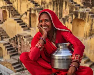 Indian woman in red clothing resting inside stepwell in village near Jaipur, Rajasthan, India.