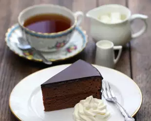 Homemade sachertorte, Austrian chocolate cake with a dollop of whipped cream and some tea 