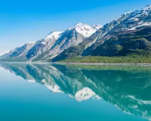 Snowy mountains being reflected on clear waters in Glacier Bay National Park, Alaska