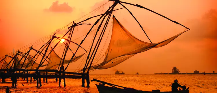 A sunset over fishing nets and boat in Cochin (Kochi), India