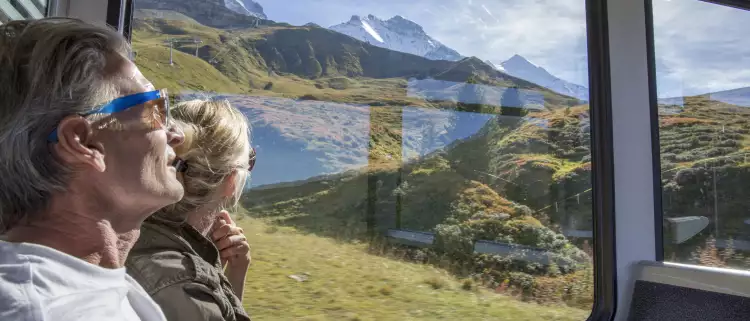 Mature couple in moving train enjoying the passing view of the Swiss alps and alpine area.