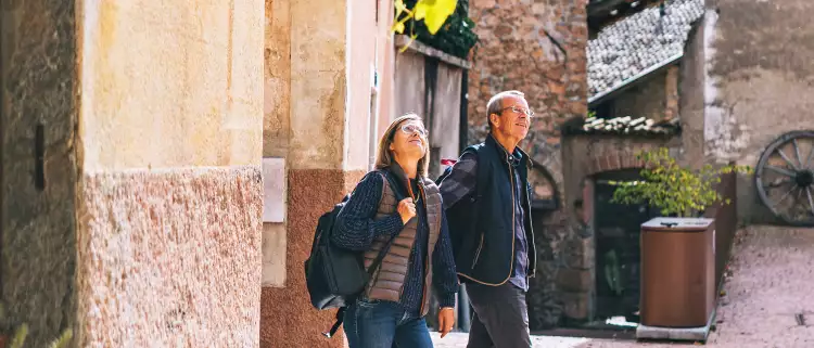 Mature couple walking and holding hands through a sunny European city