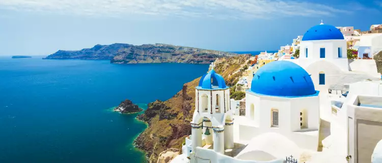 Aerial view of white church with blue dome roof in Oia town, Santorini Island, Greece