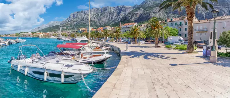 Makarska harbor under a blue cloudy sky, surrounded by the Croatia mountain range
