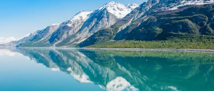 Snowy mountains being reflected on clear waters in Glacier Bay National Park, Alaska