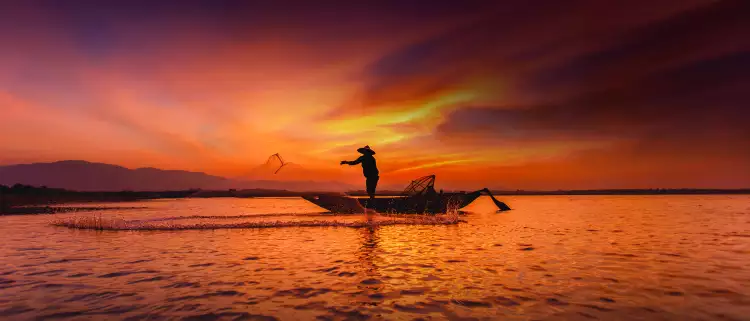 Silhouette of traditional fisherman throwing net fishing inle lake at sunrise time, Myanmar