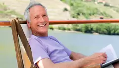 Smiling man relaxing in a chair while reading, on a boat deck