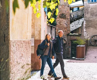 Mature couple walking and holding hands through a sunny European city