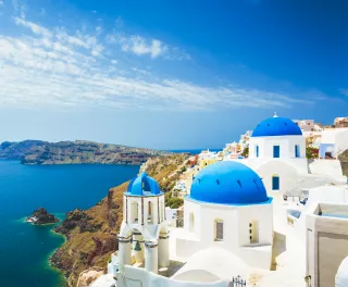 Aerial view of white church with blue dome roof in Oia town, Santorini Island, Greece