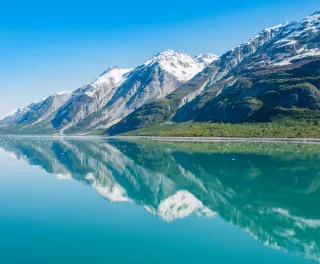 Snowy mountains being reflected on clear waters in Glacier Bay National Park, Alaska
