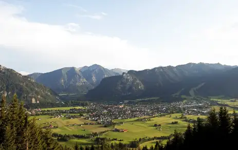 Panorama of Oberammergau with a view of mountain hilltops and green land, Germany.