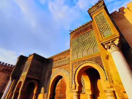 Bab El Mansour Laalej, an ornate monumental gate in the city of Meknes featuring stone archways and lattice-like patterns above stone columns 