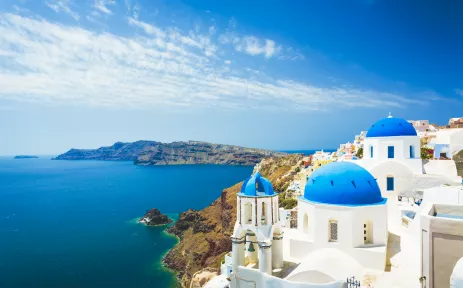 Aerial view of white church with blue dome roof in Oia town, Santorini Island, Greece