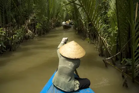 Vietnamese woman rowing a boat on the Mekong River in Vietnam