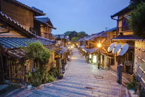 Old street of Kyoto in a Japanese town, lit by street lights under an early evening sky