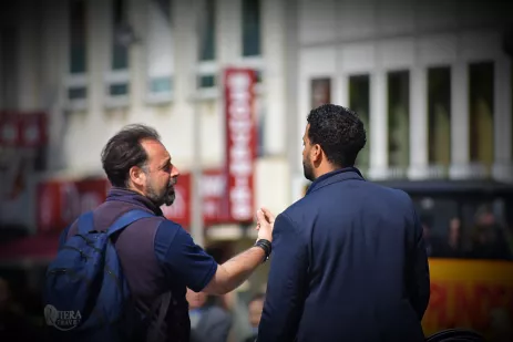 Two guys talking, one wearing a Riviera Travel backpack